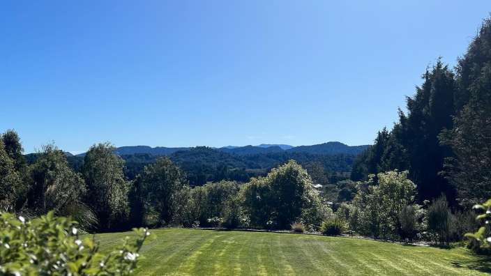 Ein großer grüner Rasen mit Bäumen und Bergen im Hintergrund