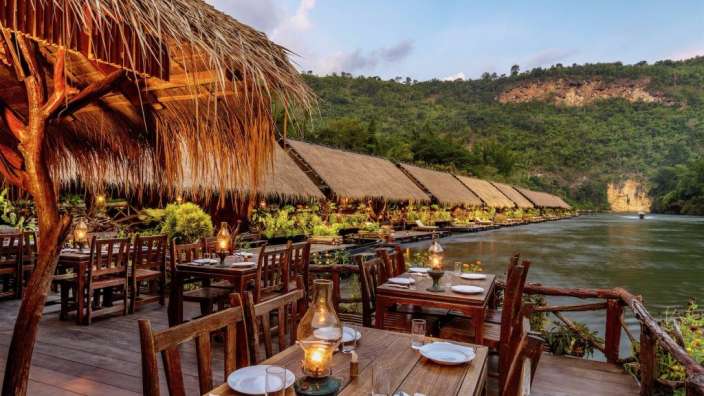Tische und Stühle auf einem Holzdeck neben einem Fluss