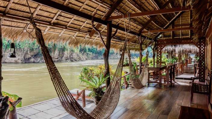 Hängematten hängen an einer überdachten Veranda mit Blick auf einen Fluss