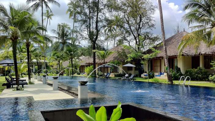 Ein großer Swimmingpool mit Wasserfontänen umgeben von Palmen