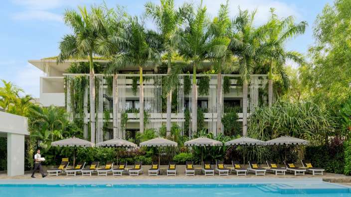 Ein Mann geht neben einem großen Swimmingpool