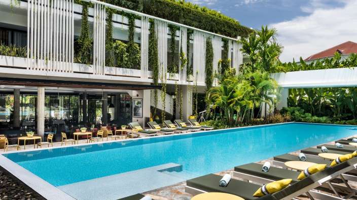 Ein großer Swimmingpool mit Liegestühlen und Tischen davor