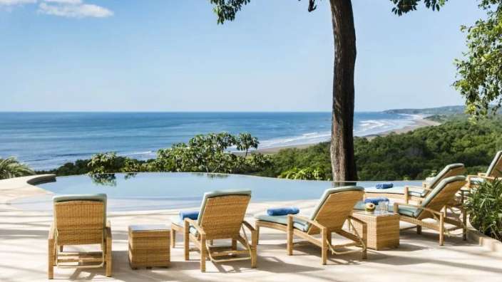 Liegestühle stehen neben einem Infinity-Pool mit Blick auf das Meer .