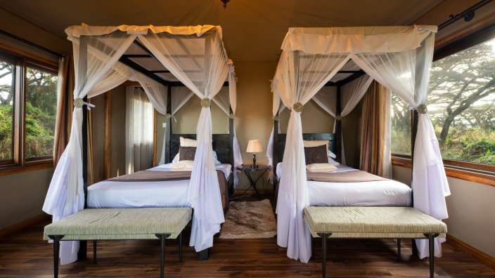 Zwei Betten mit weißen Vorhängen stehen nebeneinander