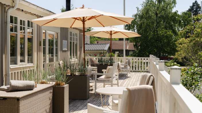 Ein Deck mit Tisch und Stühlen und Regenschirmen an einem sonnigen Tag