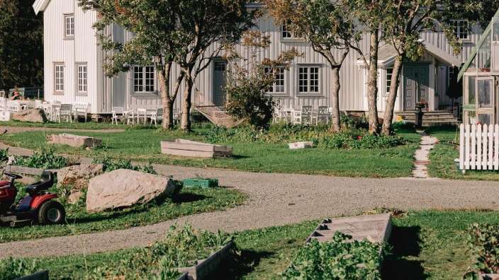 Ein kleiner Traktor steht vor einem großen weißen Haus