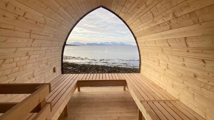 Eine Holzsauna mit Bänken und einem Fenster mit Blick auf den Ozean