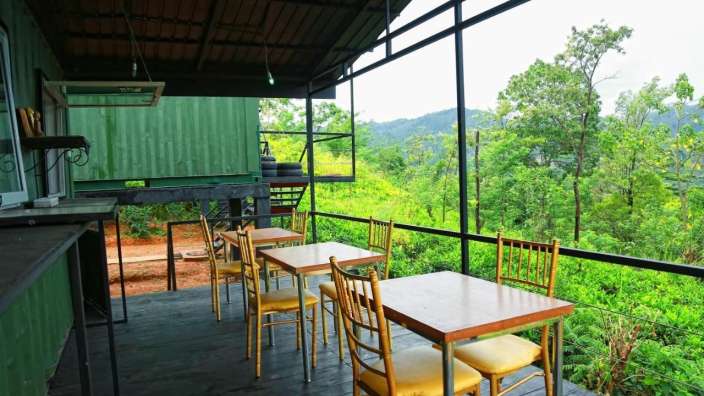 Tische und Stühle auf einem Deck mit Blick auf einen Wald