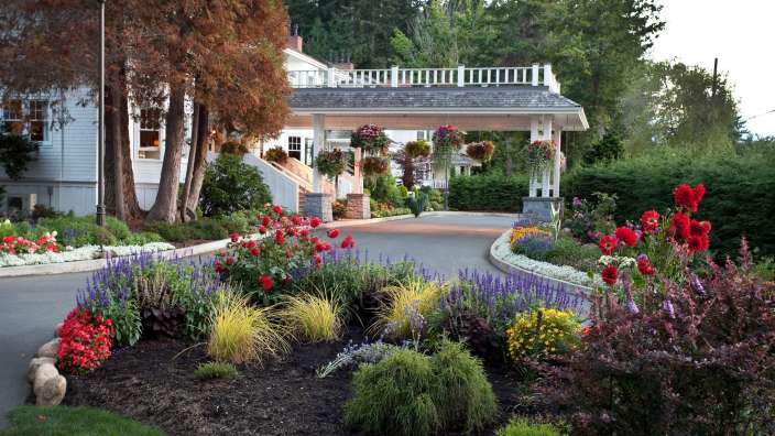Ein farbenfrohes Blumenbeet vor einem weißen Haus