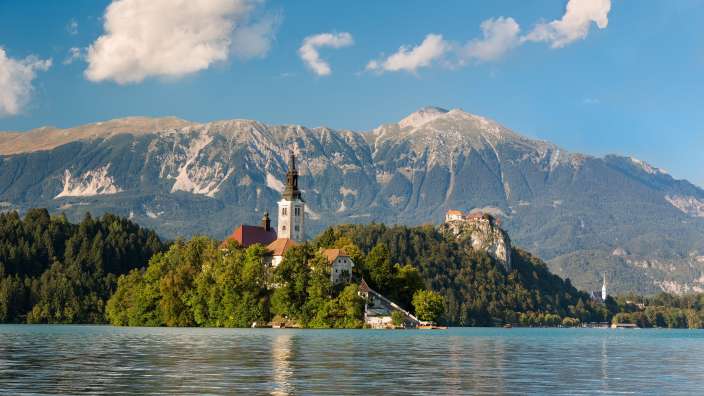 Eine Kirche auf einer kleinen Insel im See mit Bergen im Hintergrund