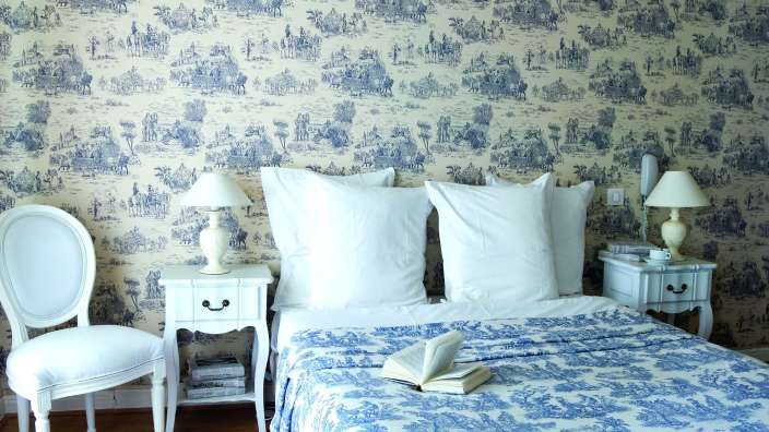 Ein Schlafzimmer mit blau-weißer Tapete und einem Bett