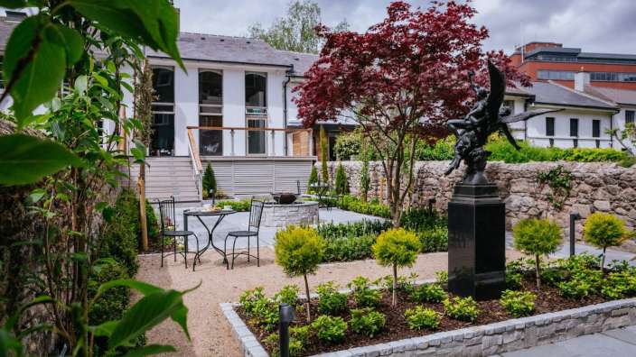 Ein Garten mit einem Tisch und Stühlen und einer Statue