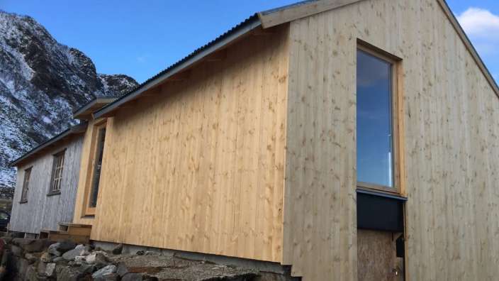 Ein Holzgebäude mit einem Fenster und einem Berg im Hintergrund