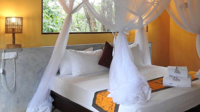 Ein Bett mit einem weißen Vorhang und zwei Handtüchern mit der Aufschrift ' ayurveda ' darauf