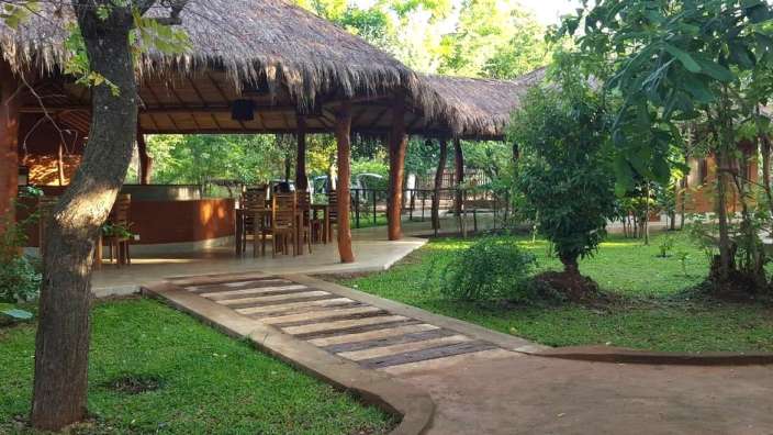 Ein kleines Gebäude mit Strohdach und Tisch und Stühlen