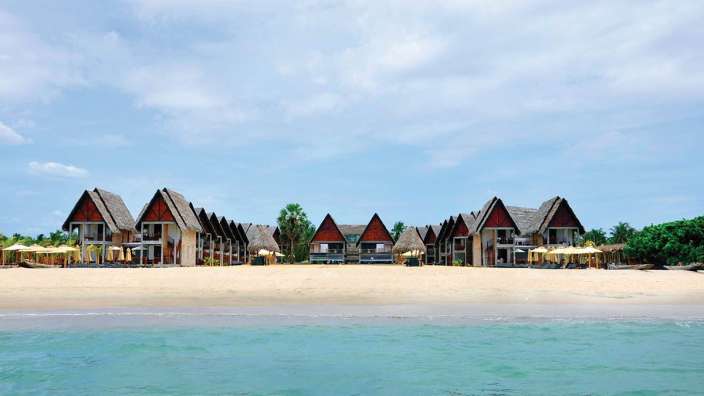Ein Strand mit vielen Hütten und Sonnenschirmen