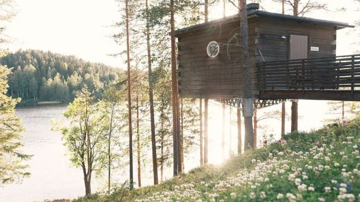 Ein kleines Holzhaus steht auf einem Hügel mit Blick auf einen See