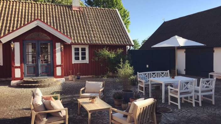 Ein kleines rotes Haus mit einem Tisch und Stühlen davor