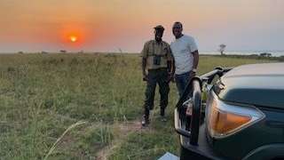 Zwei Männer stehen neben einem Auto in einem Feld .