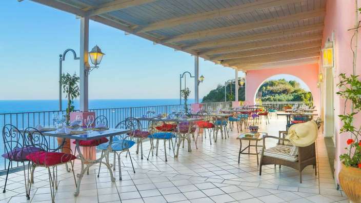 Tische und Stühle auf einem Balkon mit Blick auf den Ozean