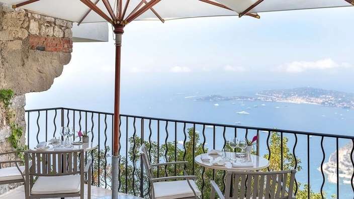 Ein Tisch und Stühle auf einem Balkon mit Blick auf das Meer