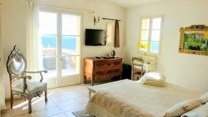 Ein Schlafzimmer mit einem Bett, einem Stuhl, einer Kommode und einem Fernseher