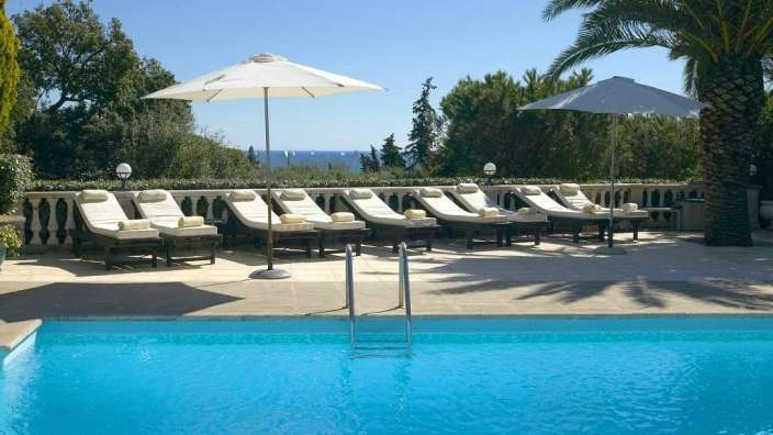 Ein Swimmingpool mit Liegestühlen und Sonnenschirmen umgeben