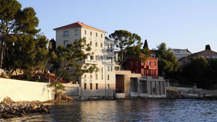 Ein weißes Gebäude neben einem roten Gebäude am Wasser