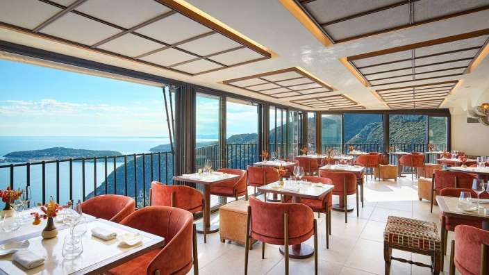 Ein Restaurant mit vielen Tischen und Stühlen mit Blick auf das Meer