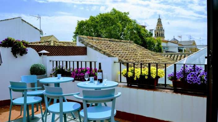 Ein Balkon mit blauen Stühlen und Tischen und einem Turm im Hintergrund