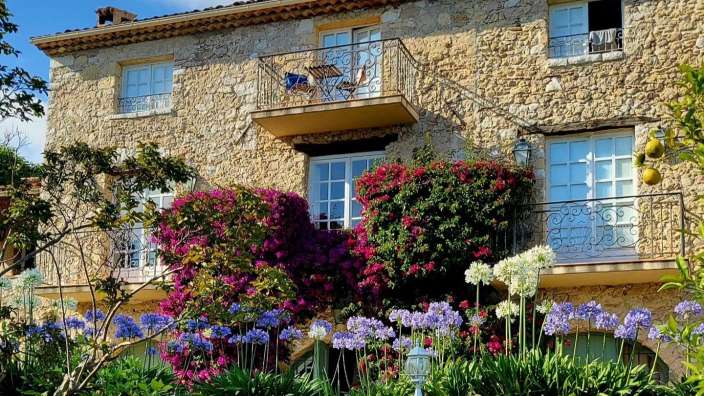Ein großes Steinhaus mit einem Balkon und vielen Blumen
