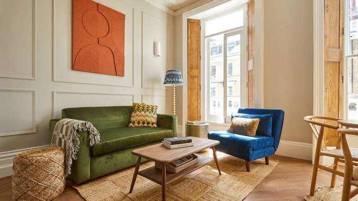 Ein Wohnzimmer mit einer grünen Couch und zwei blauen Stühlen