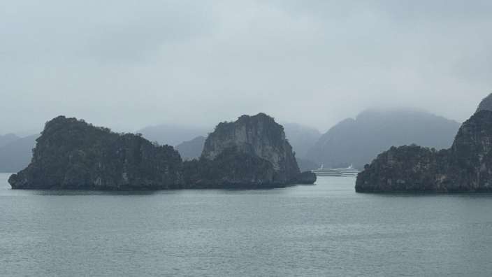 Ein großes Kreuzfahrtschiff fährt an einem bewölkten Tag zwischen den Felsen im Ozean vorbei