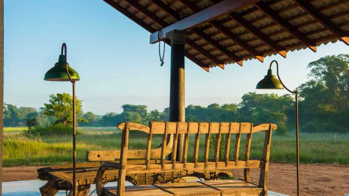 Eine Holzbank steht unter einem Dach mit zwei grünen Lampen