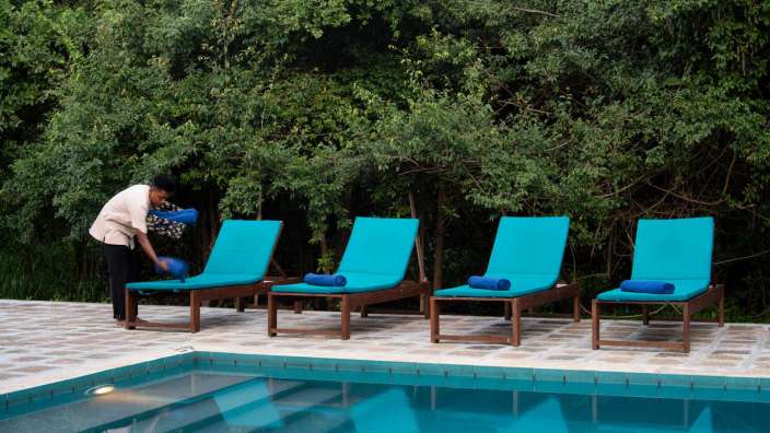 Eine Frau wäscht Liegestühle neben einem Swimmingpool