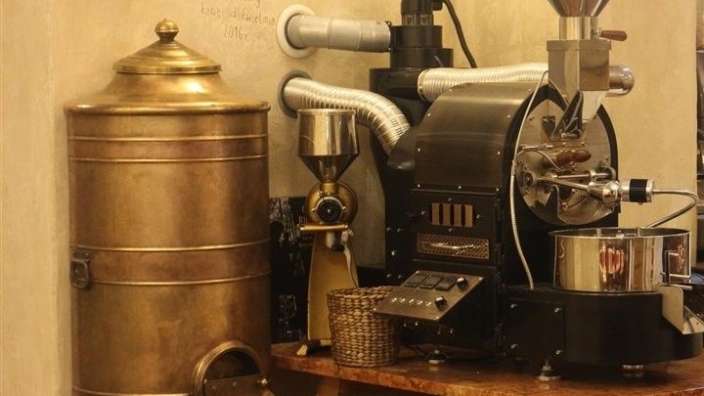 Eine Kaffeemühle steht auf einem Tisch neben einem alten Behälter