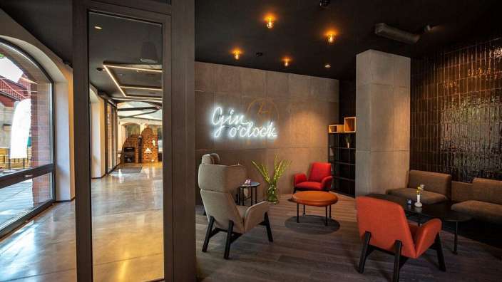 Ein Wohnzimmer mit Stühlen und einem neonschild, das sagt gin o'clock