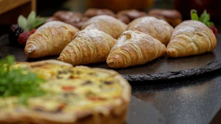 Einige Croissants auf einem Tisch neben einem quiche