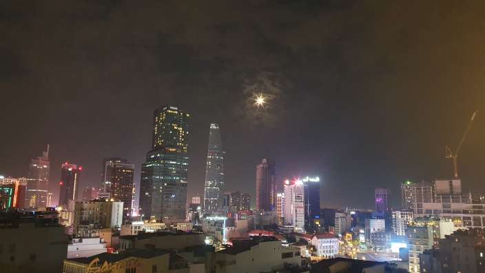 Eine Stadt bei Nacht mit einem riesigen Gebäude mit der Aufschrift ' saigon ' darauf