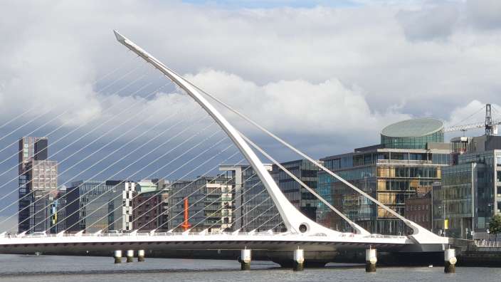 Eine weiße Brücke über einen Fluss mit Gebäuden im Hintergrund
