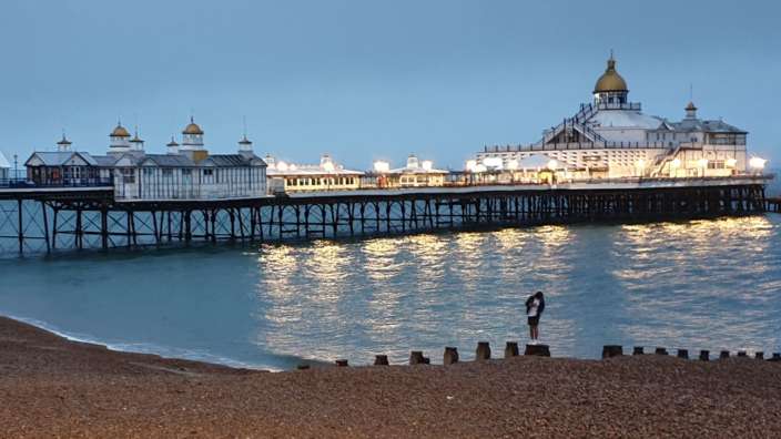 Eine Frau steht auf einem Kieselstrand in der Nähe eines Piers