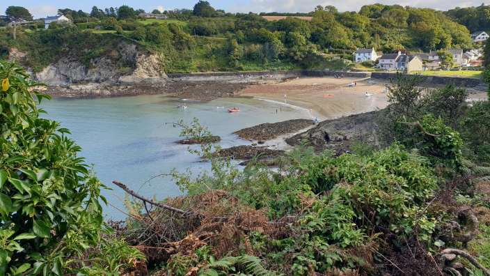 Ein Blick auf einen Strand mit einem kleinen Dorf im Hintergrund