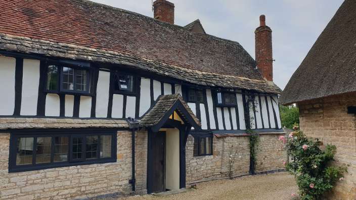 Ein Schwarz-Weiß-Haus mit vielen Fenstern und einem Strohdach