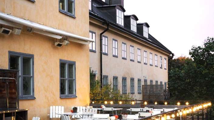 Ein Gebäude mit vielen Fenstern und einer Terrasse mit Tischen und Stühlen