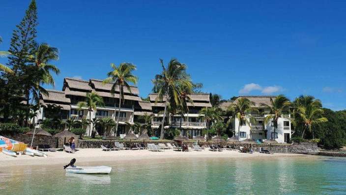 Ein weißes Boot schwimmt vor einem Hotel am Strand