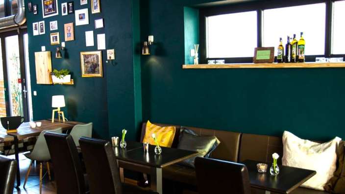 Eine Reihe von Tischen und Stühlen in einem Restaurant mit grünen Wänden