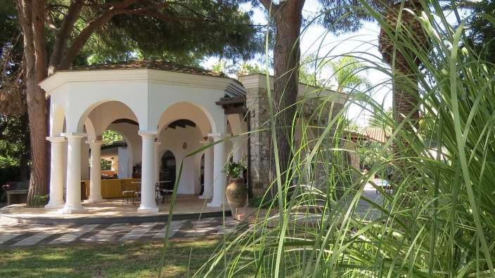 Ein weißer Pavillon mit weißen Säulen und Bäumen im Hintergrund