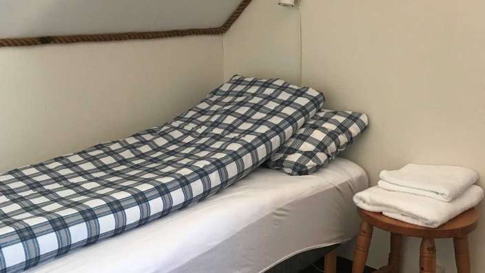 Ein Bett mit einem blau-weiß karierten Bettbezug