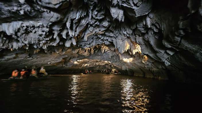 Eine Gruppe von Menschen sitzt in einem Boot in einer Höhle