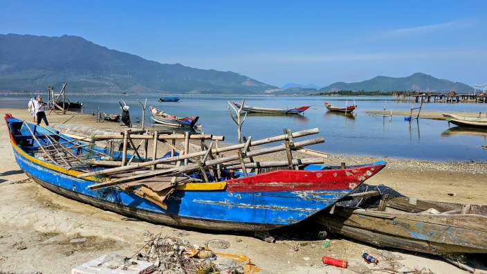 Ein blaues und rotes Boot sitzt am Strand